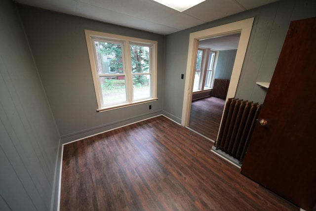 spare room featuring dark wood-type flooring and radiator