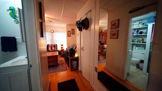 hall with light hardwood / wood-style flooring, sink, built in shelves, and a paneled ceiling