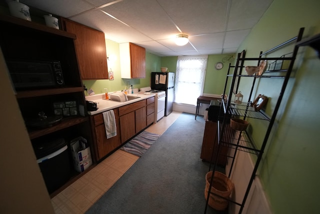 kitchen with stainless steel refrigerator, a paneled ceiling, sink, light carpet, and white gas stove