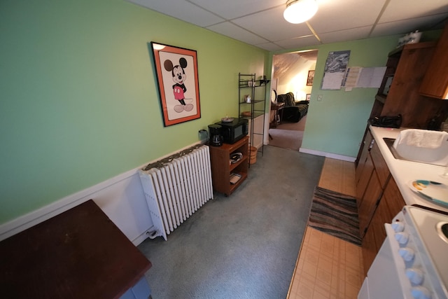 kitchen featuring dark carpet, a drop ceiling, radiator heating unit, and sink