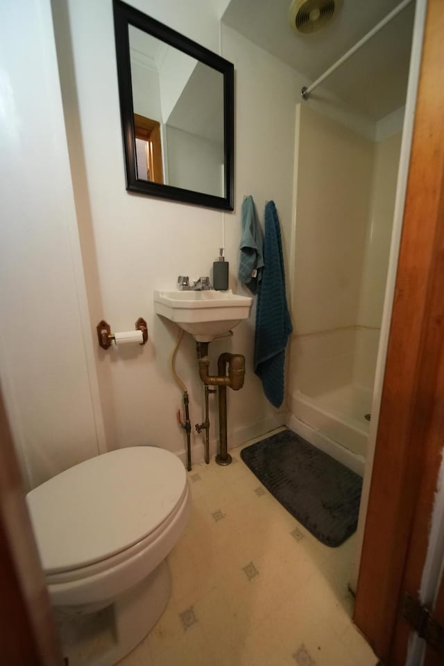 bathroom featuring tile flooring, toilet, walk in shower, and sink