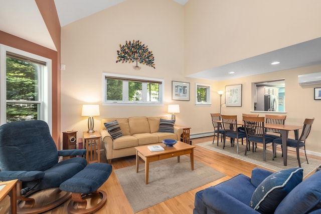 76 Heritage Dr Unit 5, Wells, ME 04090 - living room with a wall mounted AC, plenty of natural light, wood finished floors, a baseboard heating unit, and high vaulted ceiling