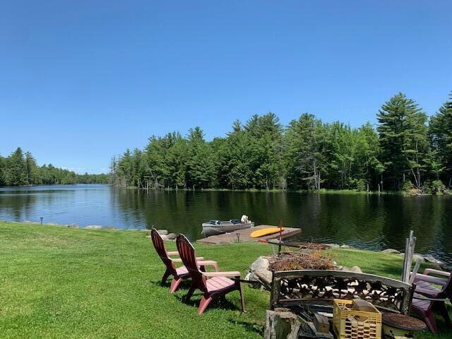 view of property's community featuring a lawn, a fire pit, and a water view