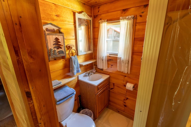 bathroom featuring toilet, wooden walls, and vanity