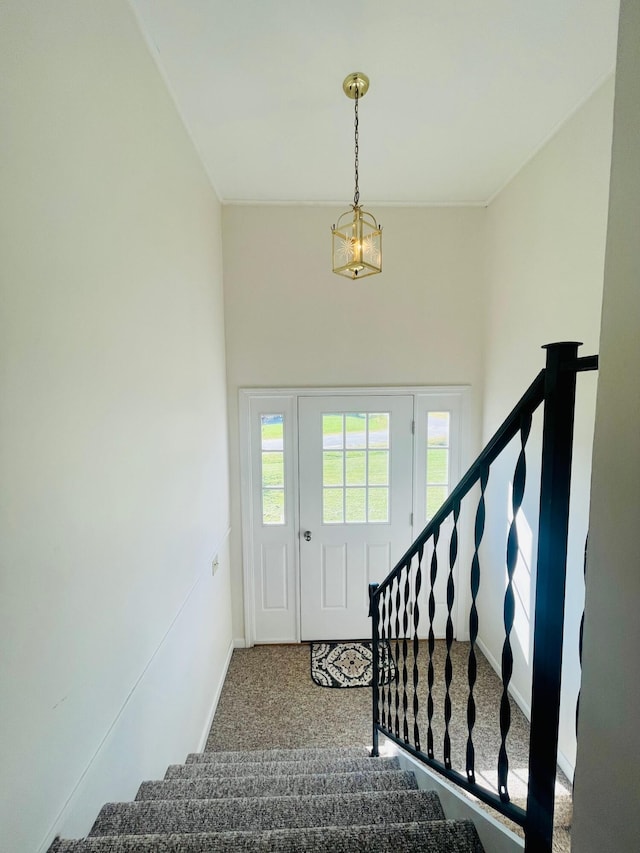 carpeted foyer entrance featuring a notable chandelier and a towering ceiling