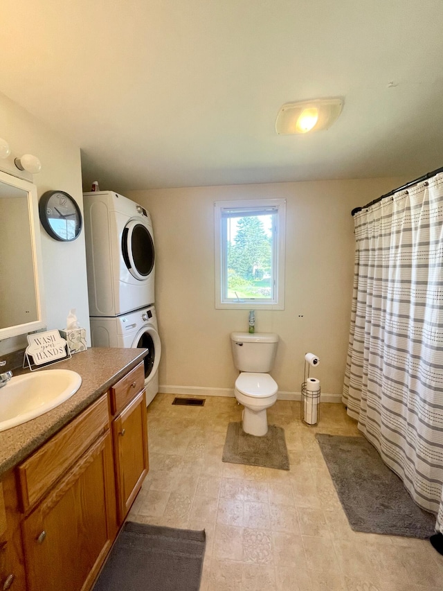 bathroom featuring tile flooring, stacked washer / drying machine, toilet, and vanity