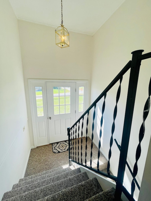 foyer featuring a chandelier, carpet, and a towering ceiling