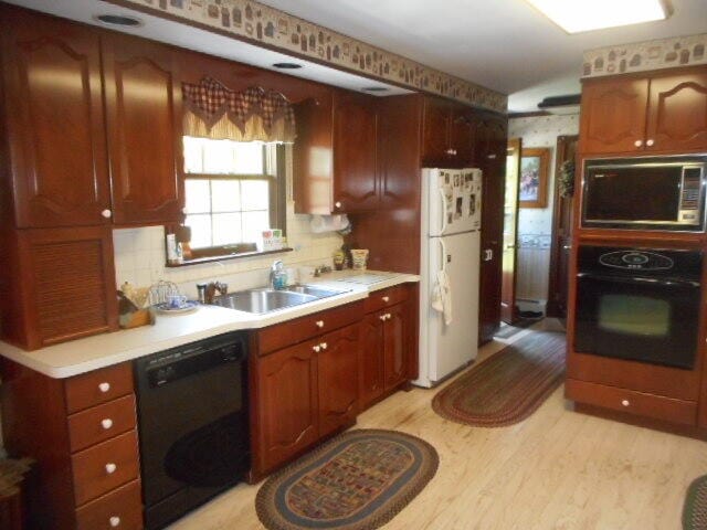 kitchen featuring backsplash, light wood-type flooring, sink, and black appliances