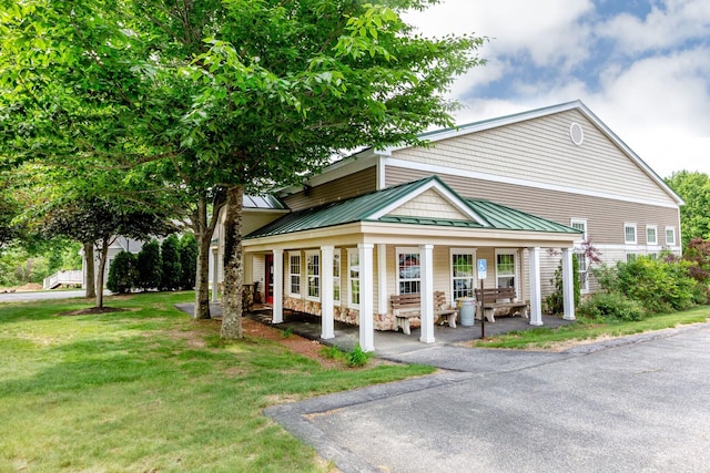 view of front of house featuring covered porch, metal roof, a standing seam roof, and a front yard