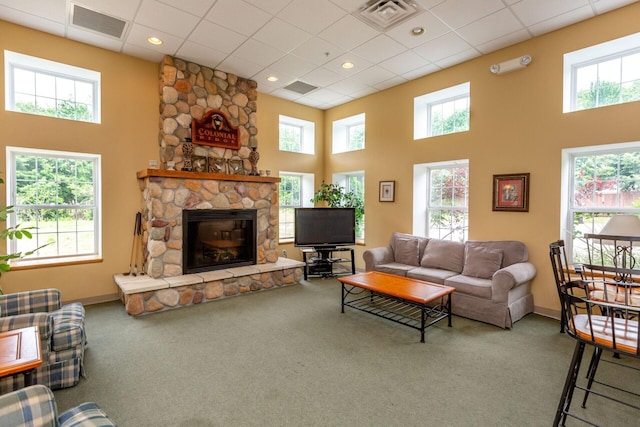 living area with a healthy amount of sunlight, a high ceiling, visible vents, and carpet flooring