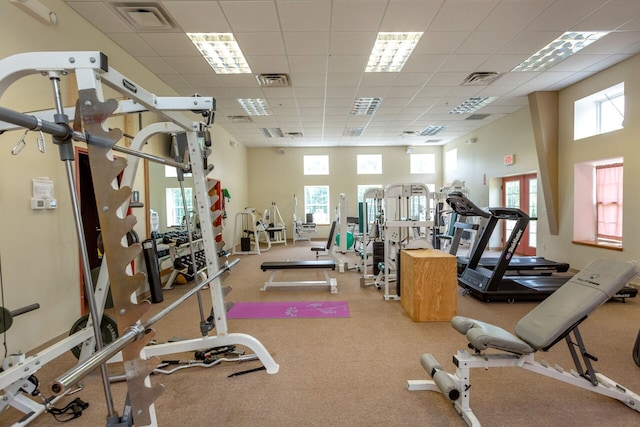 workout area featuring a paneled ceiling, a high ceiling, and visible vents