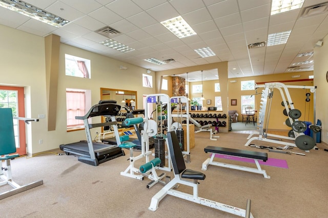 workout area featuring a towering ceiling, visible vents, and a drop ceiling