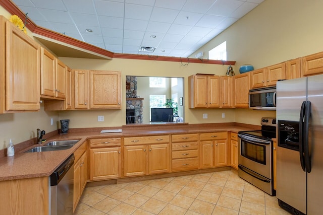 kitchen with visible vents, a peninsula, stainless steel appliances, a sink, and light tile patterned flooring