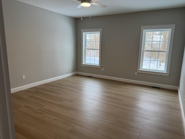 empty room with baseboards, a ceiling fan, and light wood-style floors