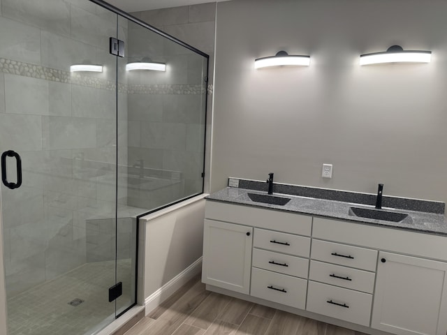 full bath featuring double vanity, a stall shower, and a sink