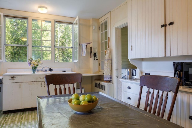 kitchen with radiator heating unit, light tile floors, and white cabinetry