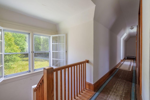 hall featuring carpet floors, a healthy amount of sunlight, a baseboard heating unit, and lofted ceiling