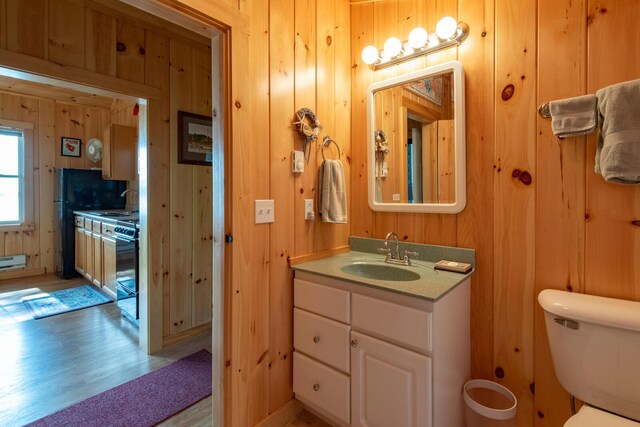 228 Starbird Ln, Rome, ME 04963 - bathroom featuring wood walls, wood finished floors, toilet, vanity, and a baseboard radiator