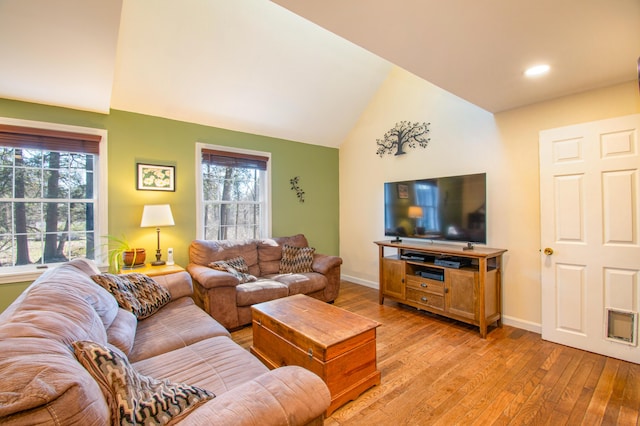living room featuring light wood finished floors, baseboards, and lofted ceiling
