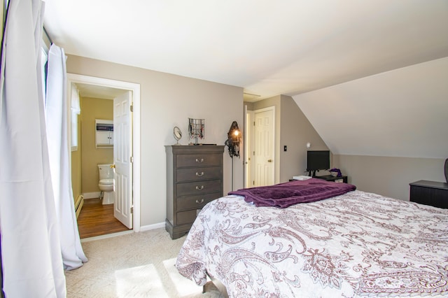 bedroom featuring a baseboard heating unit, baseboards, ensuite bath, vaulted ceiling, and light colored carpet