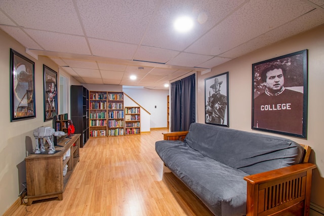 sitting room with a drop ceiling, wood finished floors, and baseboards