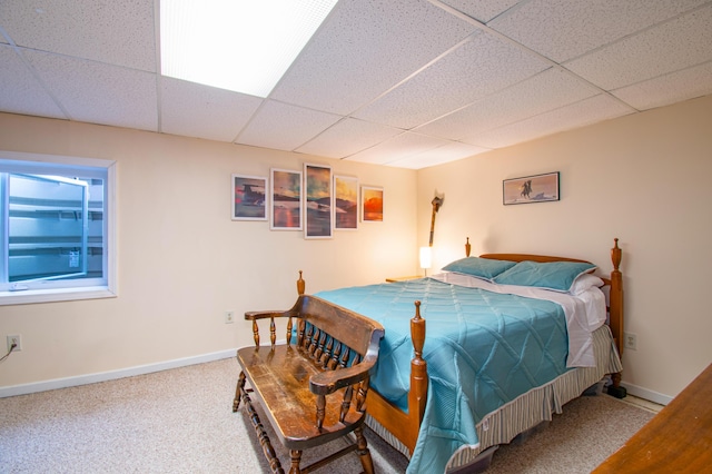 carpeted bedroom featuring a paneled ceiling and baseboards