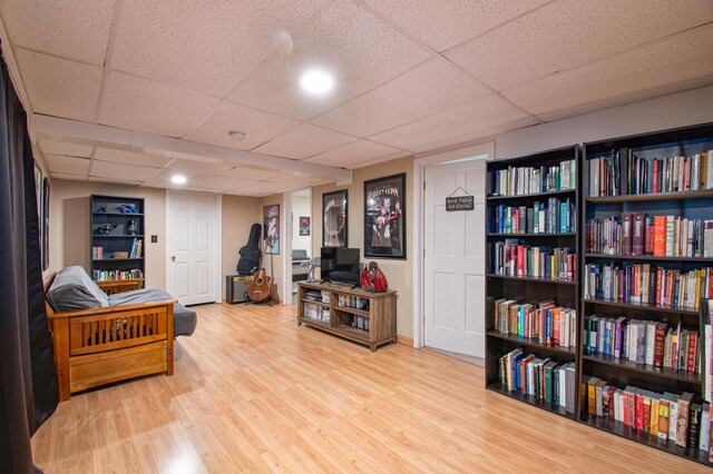 living area with a drop ceiling and wood finished floors