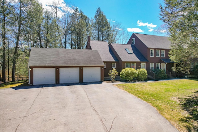 view of front of home with aphalt driveway, roof with shingles, an attached garage, a front yard, and a chimney