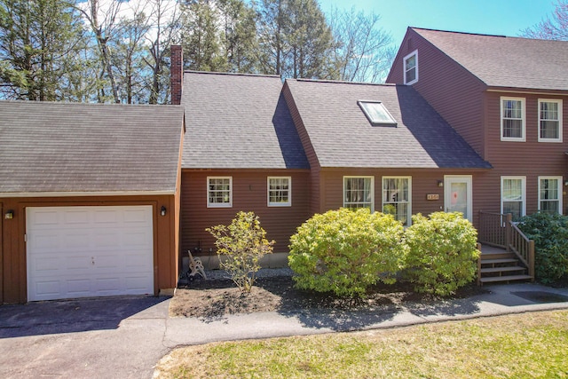 view of front of home featuring roof with shingles, a chimney, a garage, and aphalt driveway