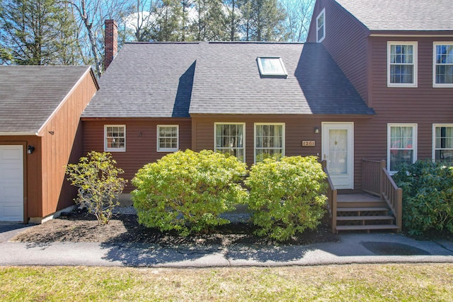 view of front facade featuring roof with shingles and a chimney