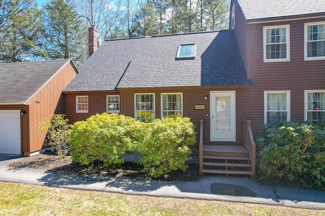 view of front of house featuring a chimney, a shingled roof, and a garage