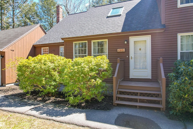 entrance to property with roof with shingles and a chimney