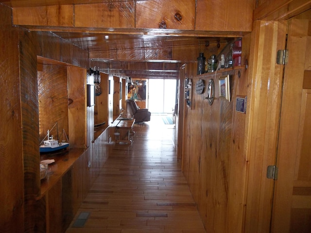 hallway featuring dark hardwood / wood-style flooring and wooden walls