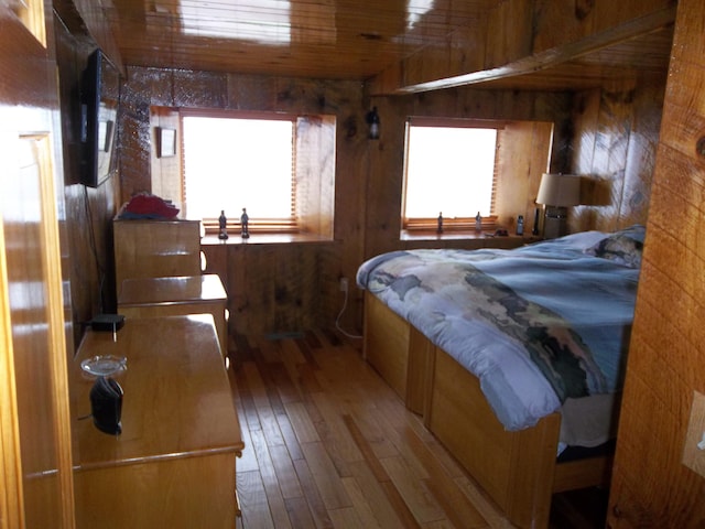 bedroom with hardwood / wood-style flooring and wooden walls