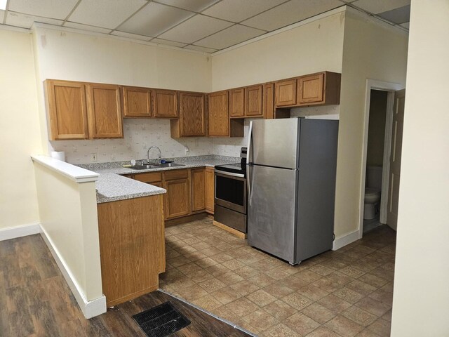 55 Cony St, Augusta, ME 04330 - kitchen featuring appliances with stainless steel finishes, a sink, a peninsula, brown cabinetry, and baseboards