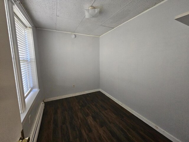 55 Cony St, Augusta, ME 04330 - empty room featuring a baseboard heating unit, dark wood-style flooring, baseboards, and a drop ceiling