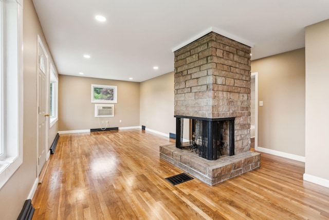 7 Alweber Rd, Windham, ME 04062 - unfurnished living room with a fireplace, light wood-style floors, a wall mounted AC, baseboards, and a baseboard radiator