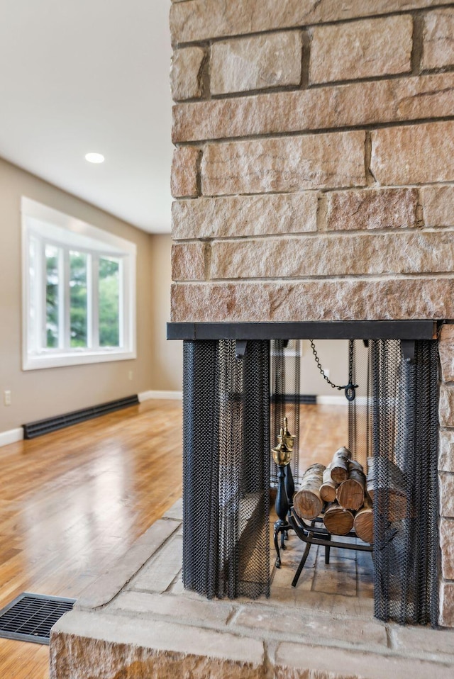 7 Alweber Rd, Windham, ME 04062 - detailed view of a multi sided fireplace, a baseboard radiator, wood finished floors, and baseboards