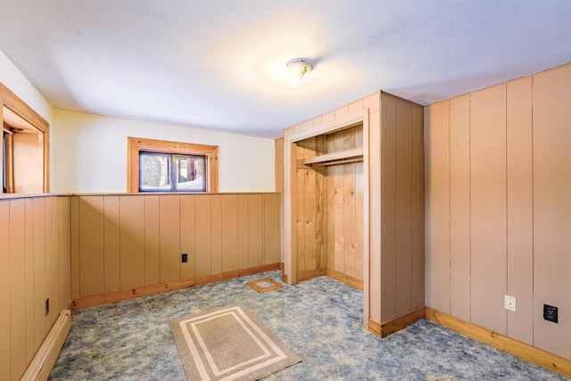 bedroom featuring a baseboard radiator, a closet, light carpet, and wood walls