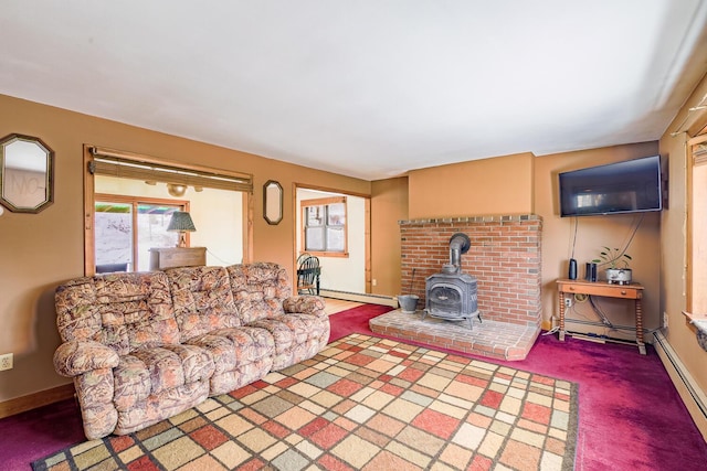 living area featuring a baseboard heating unit, dark colored carpet, a wood stove, and baseboards