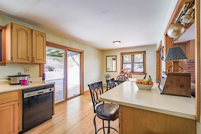 kitchen featuring plenty of natural light, black dishwasher, a kitchen bar, and light countertops