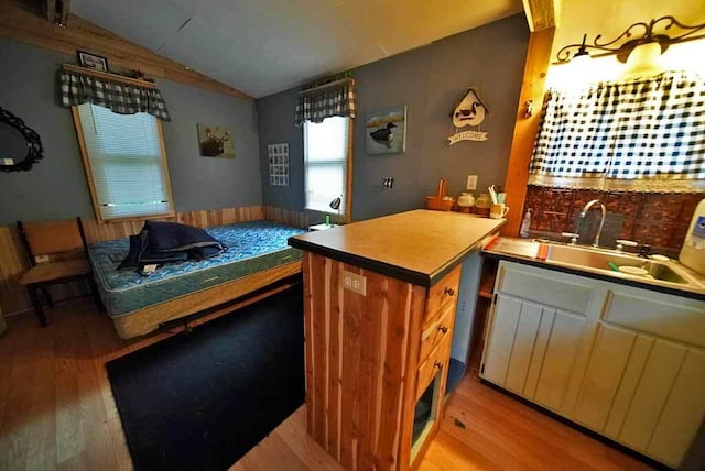 kitchen with lofted ceiling, light hardwood / wood-style flooring, kitchen peninsula, and sink