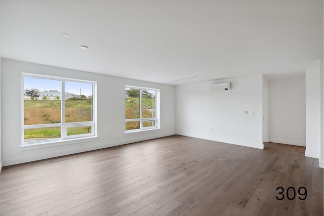 empty room featuring a wall mounted AC and wood-type flooring