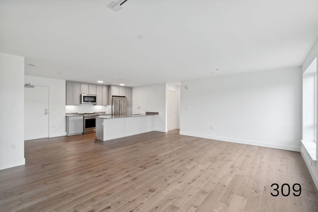 unfurnished living room with light hardwood / wood-style floors and sink