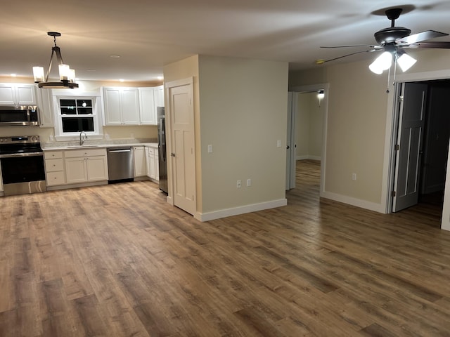 kitchen featuring pendant lighting, white cabinets, stainless steel appliances, and ceiling fan with notable chandelier