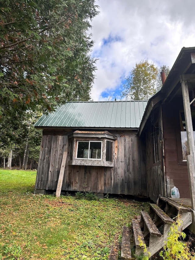 view of side of home with a lawn and an outdoor structure