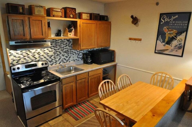 kitchen featuring backsplash, stainless steel electric range oven, sink, and light tile floors