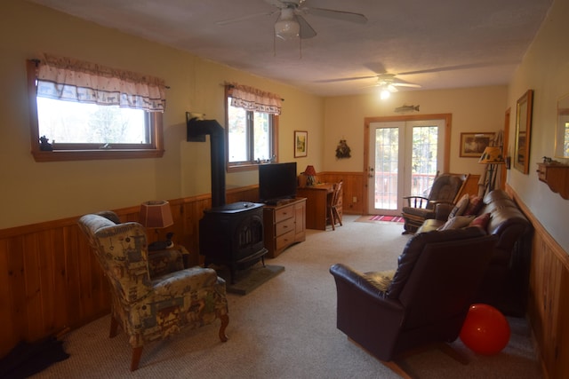 carpeted living room featuring french doors, ceiling fan, and a wood stove