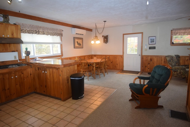 kitchen with stainless steel gas cooktop, a wall mounted AC, light carpet, hanging light fixtures, and an inviting chandelier