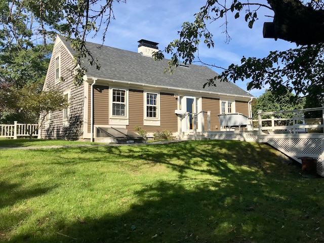 rear view of house featuring a lawn and a deck